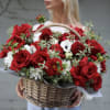 A romantic flower basket arrangement featuring lush red roses, rich burgundy blooms