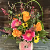 An arrangement of fresh flowers atop a Sweet Grass Farm Fragrant Candle.
This
