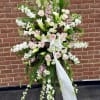 An elegant sympathy easel arrangement featuring soft white lilies, roses, and seasonal
