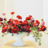 Oblong pedestal bowl filled and overflowing with red roses and ranunculas