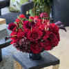 A modern red and black arrangement full of bright red Roses, with