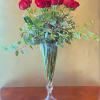 A vase full of vibrant hot pink roses, hand-arranged with ivy and