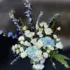 White roses, blue hydrangea, delphinium, and greens
