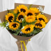 Hand held bouquet of 12 sunflowers with filler, brown paper wrap.