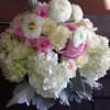 Hydrangeas, ranunculus, roses, and dusty miller arranged in a fishbowl.