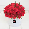 Two dozen roses perfectly arranged in a white circular box