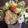 A mix of hydrangeas, lisianthus, roses, and helleborus designed in beautiful rustic
