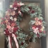 An oversized Grapevine Wreath of shades of burgundy, red, peach  and