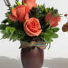 A lively arrangement of six glowing orange roses accented with fresh greenery.