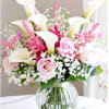This arrangement features white calla lilies, light pink roses, pink astilbe, and
