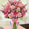 This arrangement features pink roses, lilies, and carnations accented by sprigs of