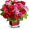This arrangement features red, pink, and light purple roses tightly clustered in