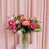 This pale pink dimpled vase showcases lush roses, ranunculus, and a selection