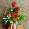 A vase of red roses and a gerbera daisy. Gerbera may be
