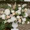 A soft, romantic altar piece filled with creamy roses, airy hydrangeas, delicate