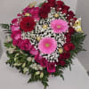 This is a heart-shaped arrangement combining roses, gerberas, and alstroemeria, with chocolates