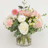 A soft spring arrangement featuring blush pink roses, seasonal blooms, and fresh