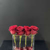 Four red roses in a narrow vase with pretty marbles