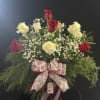 A mix of red and white roses with beautiful wintergreens in a