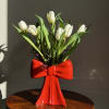 10 white tulips beautifully arranged in a specialty bow shaped vase.