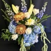 Soft shades of blue combine with seasonal best flowers. Assortment  will