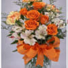 Orange roses, yellow/orange carnations white Astro in a vase. Colors may vary.