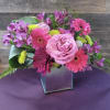 A bold, lively arrangement in a sleek, reflective vase, with vibrant colors