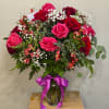 Clear vase arrangement with 16 red and pink roses, green foliage, alstroemeria