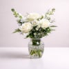 White roses with stock and greenery in a vase. 