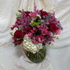 An arrangement in a glass vase of alstroemeria, statice, roses, snapdragons, lilacs