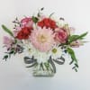 A clear glass rectangle vase, filled with pink, red and white flowers.