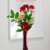 A red glass budvase filled with beautiful floral blossoms.
