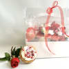 A clear presentation box filled with florals and a signature cookie from
