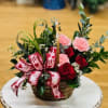 red roses and pink carnations arranged in a cute basket perfect for