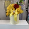 Yellow roses in a light yellow box with a single red rose