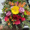 Beautiful basket with an assortment of roses and orange alstroemeria. 
