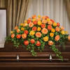 A casket spray with a stunning collection of orange and yellow roses