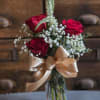 A sweet compact arrangement of 3 red roses surrounded by baby's breath