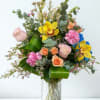 A bright, joyful mix of yellow orchids, pink carnations, blush roses, blue