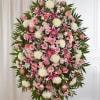 An elegant sympathy standing spray featuring soft pink roses, stargazer lilies, white