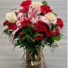 Bold red carnations and elegant white roses with delicate baby&rsquo;s breath. Finished