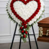 An elegant heart-shaped sympathy arrangement measuring approximately, designed with a full base