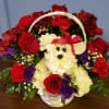 A white carnation puppy in a basket full roses and other blooms