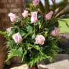 Twelve long-stemmed premium pink roses designed in a vase with complimenting lush