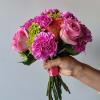 Handheld bouquet of pink roses and carnations with green accents