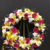 This beautiful wreath made with hot pink roses, yellow liliez white carnations