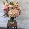 A soft, pastel floral arrangement featuring blush hydrangeas, pale pink roses, pink