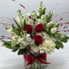 A lush mix of white and red blooms designed in a cylinder