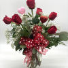 A half dozen red roses arranged in a clear vase with babies