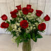 Dozen Red Roses arranged in a clear glass vase with mixed greens